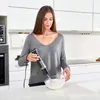 A woman is using a hand blender to whip cream in a kitchen. Podgląd zdjęcia produktu