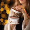 A woman is holding a Christmas-themed cookie jar filled with cookies, with bokeh lights in the background. Anteprima dell’immagine prodotto