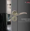 A close-up of a bronze door handle and keyhole set on a gray door, with a glimpse of an interior hallway in the background. Produktbild-Vorschau