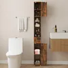 A bathroom scene with a toilet, a tall cabinet, and a sink vanity. Podgląd zdjęcia produktu
