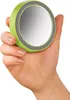 A hand holding a small, round, green mirror with a gray rim against a white background. Anteprima dell’immagine prodotto