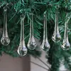 Clear glass icicle ornaments hanging from a green artificial Christmas tree. Produktbild-Vorschau