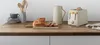 A kitchen counter with a toaster, bread, a pitcher, and utensils. Anteprima dell’immagine prodotto