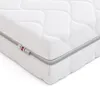 A close-up, angled view of a white mattress with a quilted pattern and a gray trim along the edge. There are small tags attached to the trim. Podgląd zdjęcia produktu