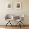 Two gray fabric chairs with black legs are placed in front of a cream-colored wall with two framed pictures above them. Voir les images du produit
