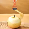 A hand is using an orange peeler to peel a yellow pear on a wooden surface. Voir les images du produit