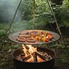 A round grill grate with food cooking over a campfire in a forest setting. Produktbild-Vorschau