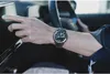 A person's hand wearing a watch is touching a car's touchscreen. Produktbild-Vorschau