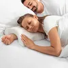 A couple sleeping in bed, with the woman using a special pillow designed to support her arm. Anteprima dell’immagine prodotto