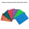 Several colorful, folded cushions are arranged in a fanned-out pattern on a white background. Produktbild-Vorschau