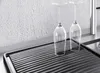 Two wine glasses are placed upside down on a black ribbed drying mat next to a sink. Podgląd zdjęcia produktu