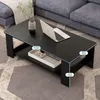 A black coffee table with a shelf is shown in a living room setting, next to a sofa. A laptop and a vase with plants are on the table. Produktbild-Vorschau