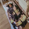 A young child is lying in a bed, wrapped in a duvet cover that has a firefighter's uniform printed on it. Produktbild-Vorschau