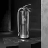 A polished metal fire extinguisher is displayed on a dark surface. Produktbild-Vorschau