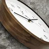 A close-up, angled view of a wooden wall clock with a white face and black hands, set against a textured gray and white background. Voir les images du produit