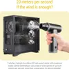 A hand is holding a black and gray dust blower, aiming it at a computer case that is filled with dust. The computer case has fans visible inside. Náhled obrázku produktu