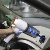 Weißer und roségoldener Auto-Luftreiniger, in einer Hand gehalten, gibt grüne blumenförmige Partikel in eine Lüftungsöffnung des Autos ab Náhľad obrázku produktu