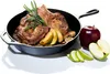 A cast iron skillet with a pork chop, apples, and herbs inside, next to whole and sliced apples. Voir les images du produit