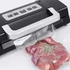 A close-up shot of a vacuum sealer machine sealing a piece of meat in a plastic bag. Podgląd zdjęcia produktu
