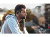 A man wearing headphones outdoors with a city skyline in the background. Produktbild-Vorschau