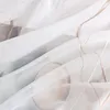 A close-up view of a white sheer fabric with a subtle wave pattern and embroidered details. Produktbild-Vorschau