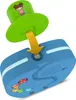 A close-up, studio shot of a blue electronic toy with a green hat-like attachment being inserted into it. The toy has colorful buttons and lights. Produktbild-Vorschau