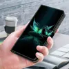 A hand holding a phone case with a butterfly design, with a coffee cup and books in the background. Produktbild-Vorschau