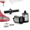 A collection of kitchen appliance attachments, including graters and a food pusher, laid out on a white background. Voir les images du produit