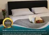 A neatly made bed with pillows and a blanket, featuring a decorative tray with a cup and cookies. Produktbild-Vorschau