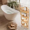 A bathroom scene with a freestanding bathtub, a wooden corner shelf unit, and decorative items. Podgląd zdjęcia produktu