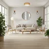 A modern living room with a sofa, chairs, coffee table, and plants, illuminated by natural light from large windows. Produktbild-Vorschau