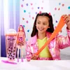 A young girl is playing with a Barbie doll and slime, with a large boba tea cup and a smaller one in the background. Podgląd zdjęcia produktu