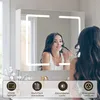A woman applying makeup in front of a lit bathroom mirror cabinet. Voir les images du produit