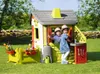 Two young children playing in a colorful playhouse in a grassy yard. Produktbild-Vorschau