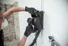 A person is using a wall slotter machine to cut a groove in a wall. Náhled obrázku produktu