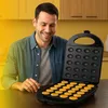 A man is smiling while looking at an open waffle maker with freshly made waffles. Voir les images du produit