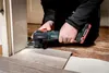 A person is using a Metabo multitool to cut flooring near a doorway. Náhľad obrázku produktu