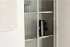 A modern cabinet with fluted glass doors and shelves, featuring a black vase. Voir les images du produit