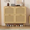 A light wood shoe cabinet with four rattan-fronted doors and a row of shoes underneath. Produktbild-Vorschau