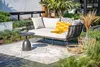 An outdoor living space with a daybed, rug, side table, and decorative baskets. Produktbild-Vorschau