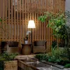 An outdoor seating area with a lamp, chairs, and a water feature. Produktbild-Vorschau