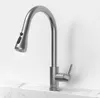 A stainless steel kitchen faucet with a pull-out spout is shown in operation, with water flowing from the spout. Podgląd zdjęcia produktu