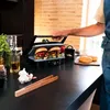 A person is using a grill to cook burgers in a kitchen. Voir les images du produit