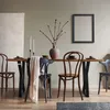 A dining table with black X-shaped legs, set with chairs, a vase of branches, and place settings. Náhľad obrázku produktu