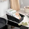 A black kitchen organizer filled with spice packets sits on a kitchen counter next to a stovetop. Náhľad obrázku produktu