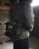 A person wearing a green jacket and black jeans, with a green hip pack attached to their waist. Produktbild-Vorschau