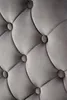 A close-up view of a tufted gray upholstered surface with button accents. Voir les images du produit