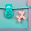 A close-up view of a teal-colored clip with a logo and a peach-colored balloon dog charm attached to a backpack. Anteprima dell’immagine prodotto