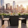 A three-piece rattan furniture set with cushions on a balcony overlooking a city skyline at sunset. Anteprima dell’immagine prodotto