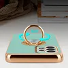 A close-up of a turquoise phone case with a gold ring holder and camera protection, resting on a light-colored surface. Náhľad obrázku produktu